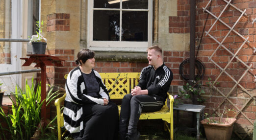 Learners Holly and Josh chatting on a bench outside the Eveson Centre