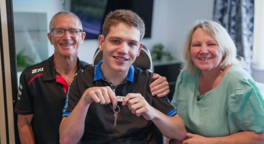 Elliot smiling in his bedroom with his parents