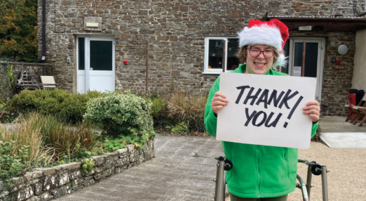 Lucy smiling, wearing a santa hat and holding a thank you card